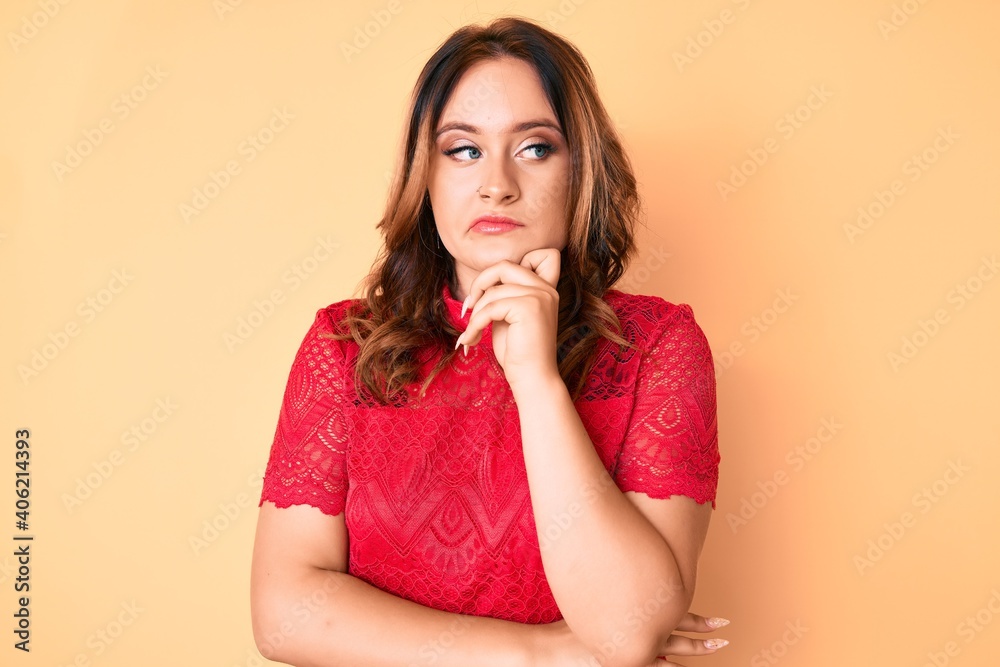 Young beautiful caucasian woman wearing casual clothes with hand on chin thinking about question, pensive expression. smiling with thoughtful face. doubt concept. Young beautiful caucasian woman wearing casual clothes with hand on chin thinking about question, pensive expression. smiling with thoughtful face. doubt concept.