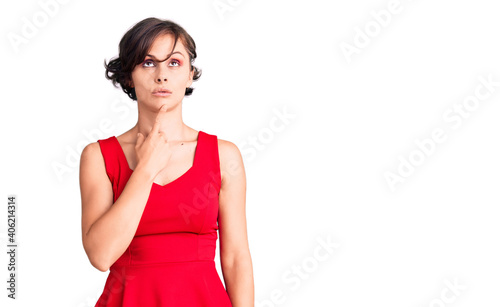 Beautiful young woman with short hair wearing casual style with sleeveless shirt thinking concentrated about doubt with finger on chin and looking up wondering