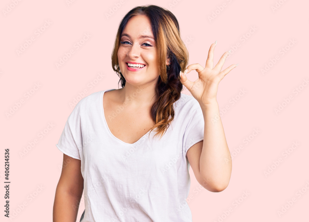Young beautiful caucasian woman wearing casual white tshirt smiling positive doing ok sign with hand and fingers. successful expression. Young beautiful caucasian woman wearing casual white tshirt smiling positive doing ok sign with hand and fingers. successful expression.