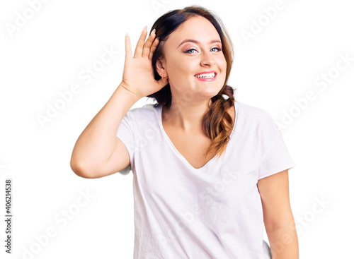 Young beautiful caucasian woman wearing casual white tshirt smiling with hand over ear listening an hearing to rumor or gossip. deafness concept.