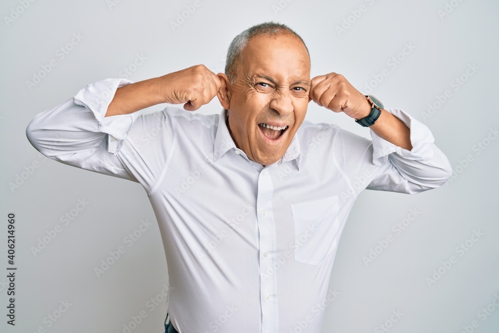 Handsome senior man wearing casual white shirt smiling pulling ears with fingers, funny gesture. audition problem Handsome senior man wearing casual white shirt smiling pulling ears with fingers, funny gesture. audition problem