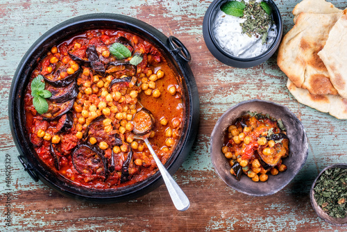 Modern style slow cooked Lebanese vegetarian eggplant stew maghmour served with chickpeas and pita bread as top view in a design pot photo