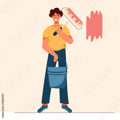 a male painter with a roller in his hand and a bucket of paint paints a wall at home, repairs with his own hands