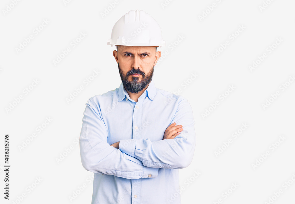 Young handsome man wearing architect hardhat skeptic and nervous, disapproving expression on face with crossed arms. negative person. Young handsome man wearing architect hardhat skeptic and nervous, disapproving expression on face with crossed arms. negative person.