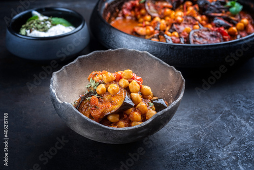 Modern style slow cooked Lebanese vegetarian eggplant stew maghmour served with chickpeas and yoghurt as close-up in a rustic design bowl photo