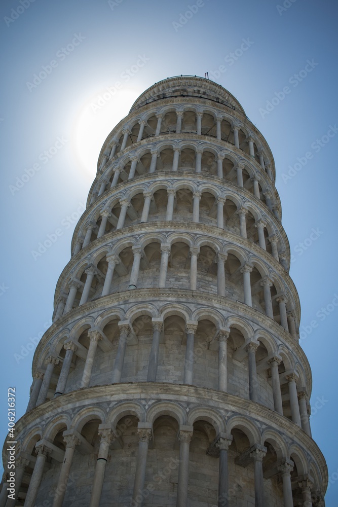 Vertical image of Leaning Tower of Pisa with shining sun behind