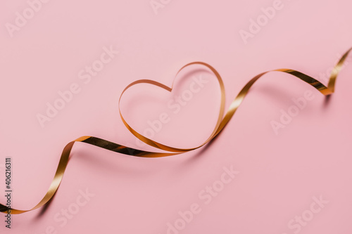 shape heart by gold ribbon on isolated pink background
