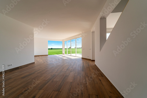 Empty room with dark wooden floating laminate flooring. House interior  wide bedroom space. Newly coutryside apartment or house with nature view. Wood floor. Real state or property management