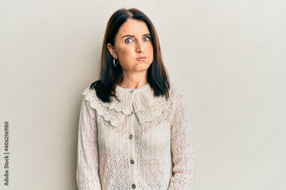 Middle age brunette woman wearing casual clothes puffing cheeks with funny face. mouth inflated with air, crazy expression. Middle age brunette woman wearing casual clothes puffing cheeks with funny face. mouth inflated with air, crazy expression.