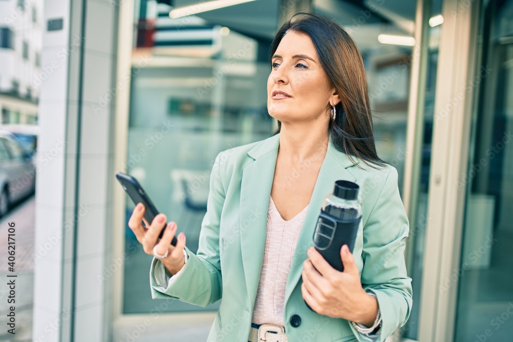 Confident business woman wearing elegant suit standing at the street using smartphone with cheerful face Confident business woman wearing elegant suit standing at the street using smartphone with cheerful face
