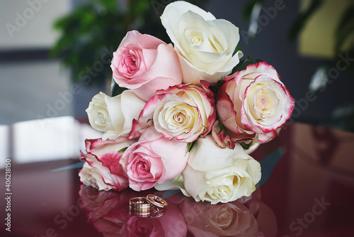 elegant wedding bouquet of white and pink rose flowers. gold wedding rings on the table. preparing for the wedding ceremony