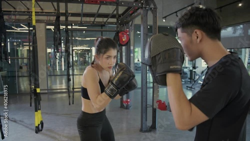 Fitness concept of 4k Resolution. Woman fighter ready to throw a punch with trainer teacher holding pads for boxing session. photo