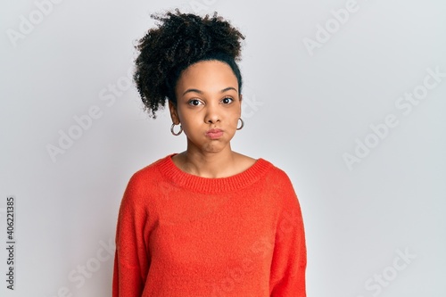 Young african american girl wearing casual clothes puffing cheeks with funny face. mouth inflated with air, crazy expression.