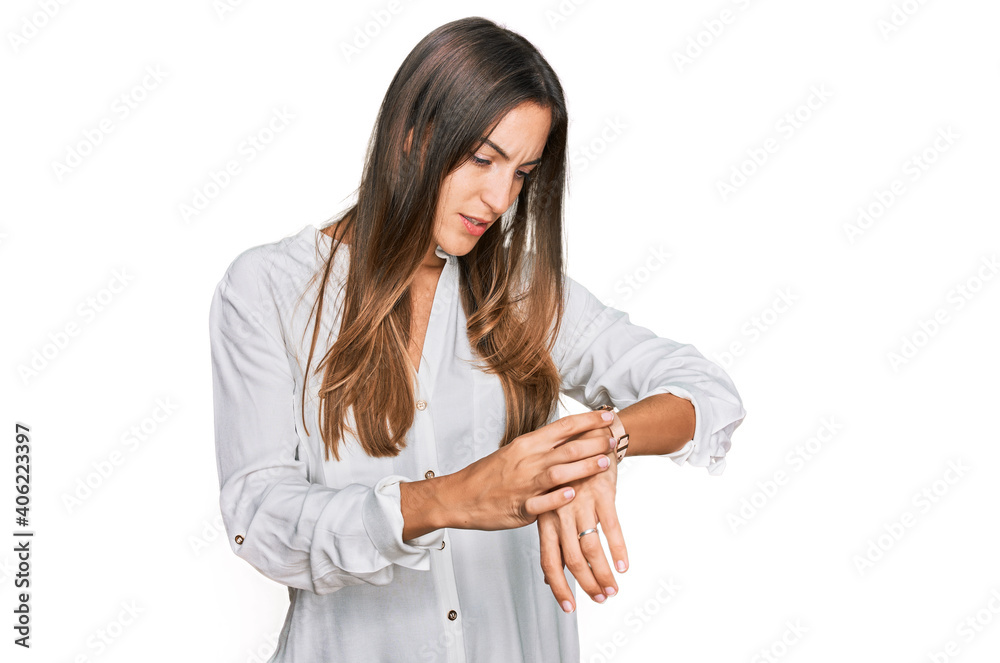 Young beautiful woman wearing casual clothes checking the time on wrist watch, relaxed and confident