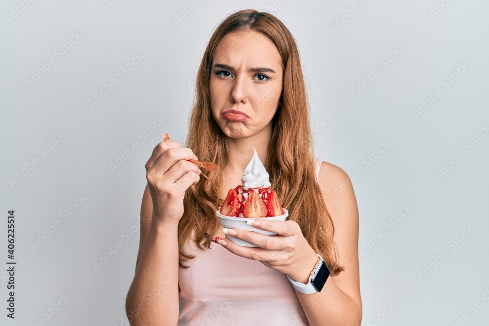 Young blonde woman eating strawberry ice cream depressed and worry for distress, crying angry and afraid. sad expression. Young blonde woman eating strawberry ice cream depressed and worry for distress, crying angry and afraid. sad expression.