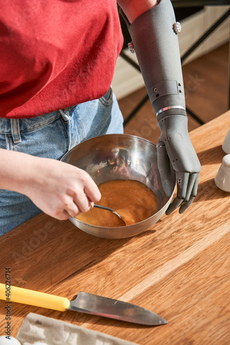 Woman with prosthesis arm preparing omelet in kitchen