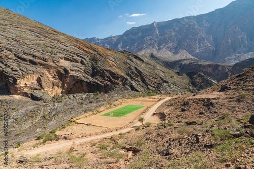 A green soccer field in the desert mountains of Oman.
