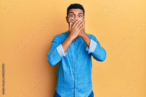Young arab man wearing casual clothes shocked covering mouth with hands for mistake. secret concept.