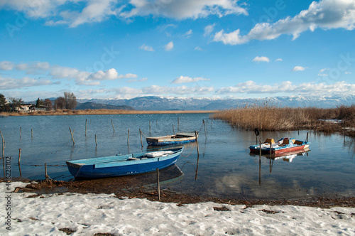 Along the shore of the lake in winter. Plants and reeds covered with snow, boats overturned by the water.