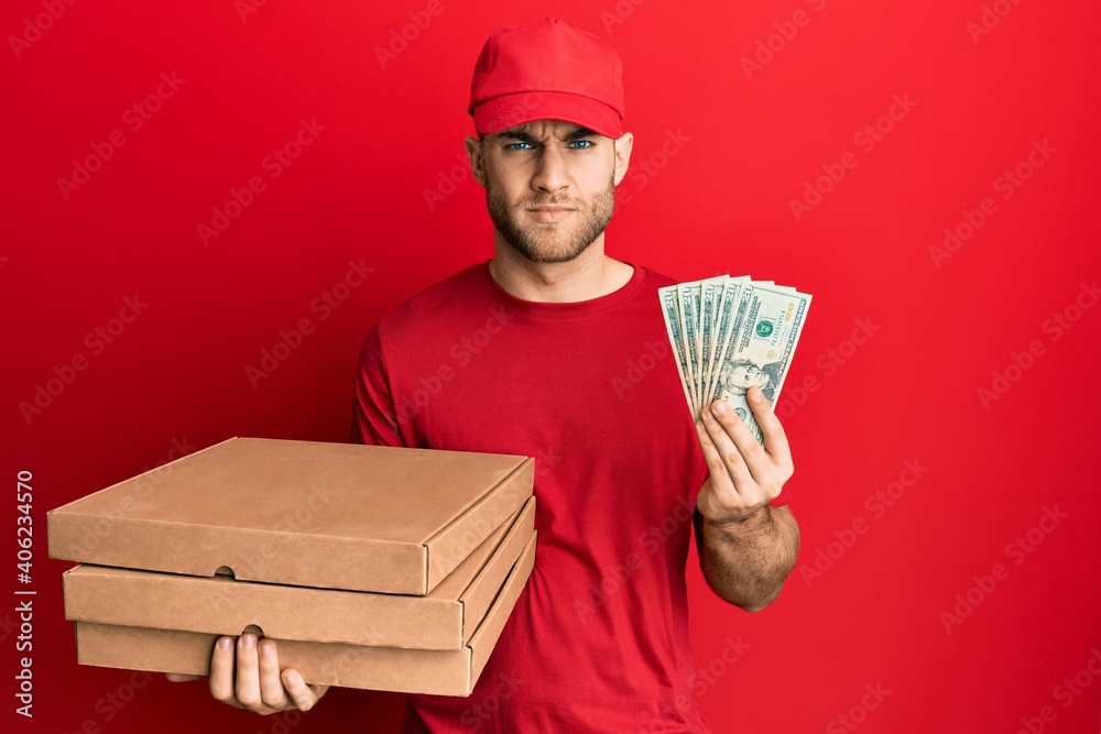 Young caucasian man holding take away food and 20 dollars skeptic and nervous, frowning upset because of problem. negative person. Young caucasian man holding take away food and 20 dollars skeptic and nervous, frowning upset because of problem. negative person.