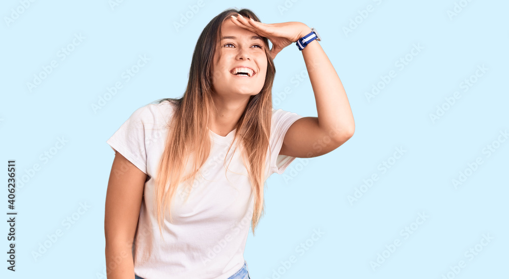 Beautiful caucasian woman wearing casual white tshirt very happy and smiling looking far away with hand over head. searching concept. Beautiful caucasian woman wearing casual white tshirt very happy and smiling looking far away with hand over head. searching concept.