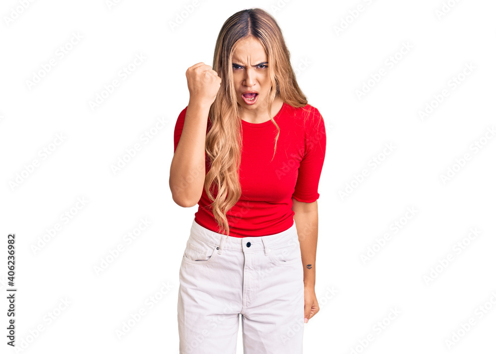 Fototapeta premium Young beautiful blonde woman wearing casual clothes angry and mad raising fist frustrated and furious while shouting with anger. rage and aggressive concept.