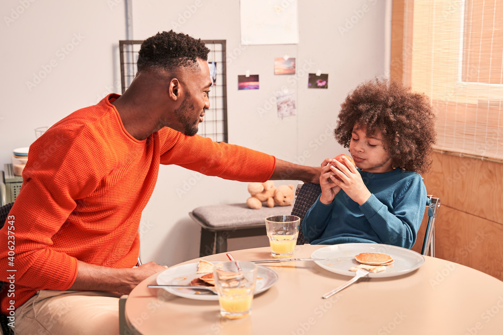 Father and son communicating at the table during breakfast Father and son communicating at the table during breakfast