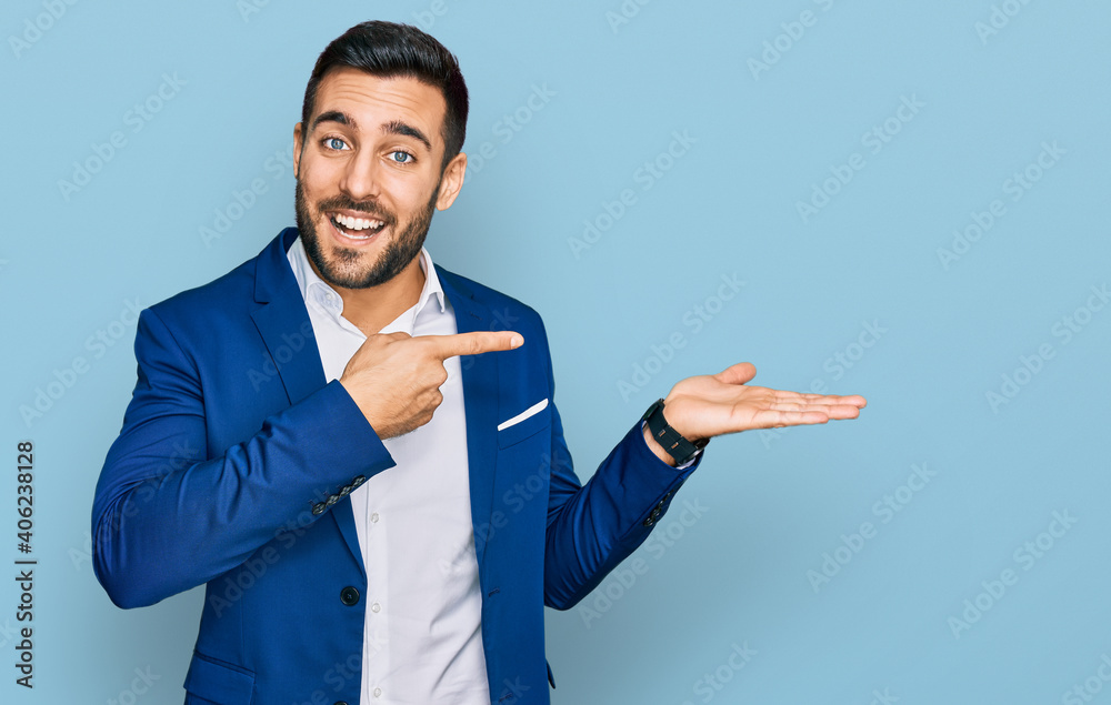 Young hispanic man wearing business jacket amazed and smiling to the camera while presenting with hand and pointing with finger. Young hispanic man wearing business jacket amazed and smiling to the camera while presenting with hand and pointing with finger.
