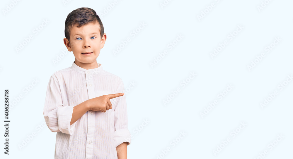 Cute blond kid wearing elegant shirt pointing aside worried and nervous with forefinger, concerned and surprised expression Cute blond kid wearing elegant shirt pointing aside worried and nervous with forefinger, concerned and surprised expression