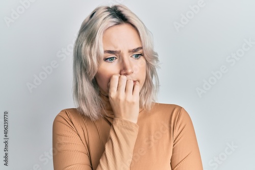 Vászonkép Young blonde girl wearing casual clothes looking stressed and nervous with hands on mouth biting nails