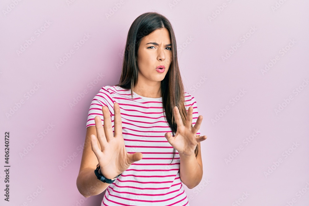 Young brunette woman wearing casual clothes over pink background moving away hands palms showing refusal and denial with afraid and disgusting expression. stop and forbidden. Young brunette woman wearing casual clothes over pink background moving away hands palms showing refusal and denial with afraid and disgusting expression. stop and forbidden.