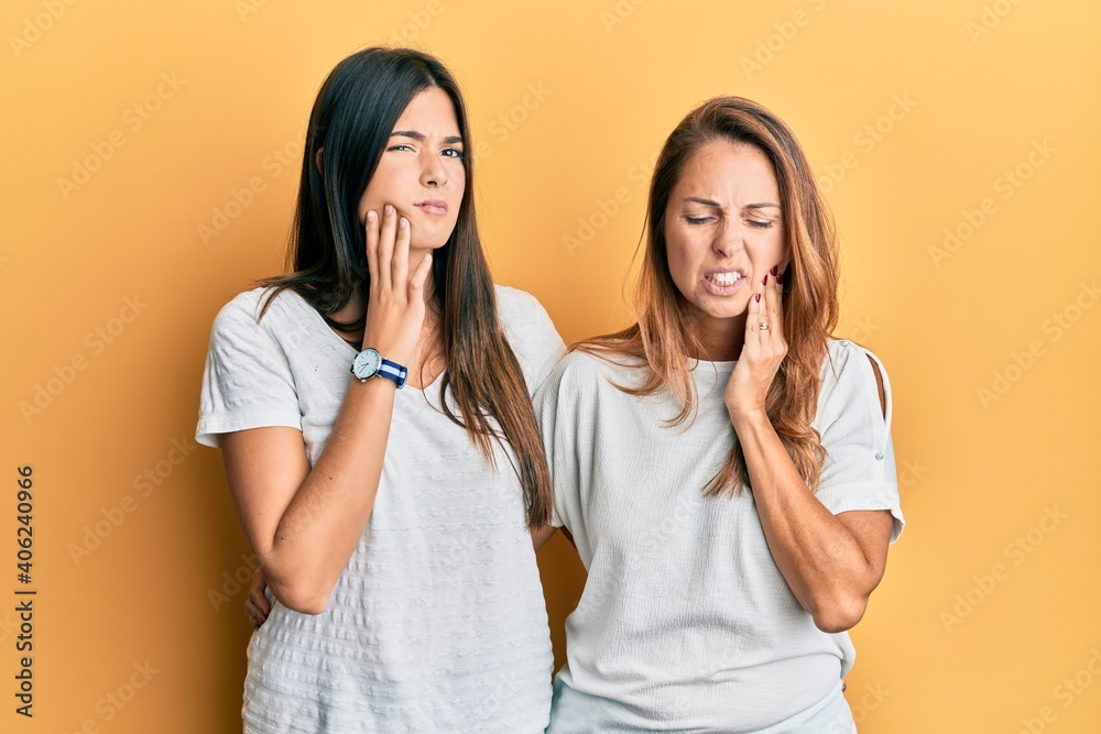 Hispanic family of mother and daughter wearing casual white tshirt touching mouth with hand with painful expression because of toothache or dental illness on teeth. dentist concept. Hispanic family of mother and daughter wearing casual white tshirt touching mouth with hand with painful expression because of toothache or dental illness on teeth. dentist concept.