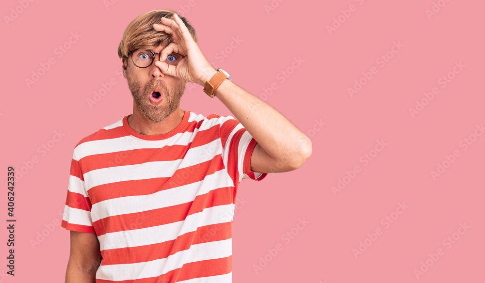 Handsome caucasian man with beard wearing casual clothes and glasses doing ok gesture shocked with surprised face, eye looking through fingers. unbelieving expression. Handsome caucasian man with beard wearing casual clothes and glasses doing ok gesture shocked with surprised face, eye looking through fingers. unbelieving expression.