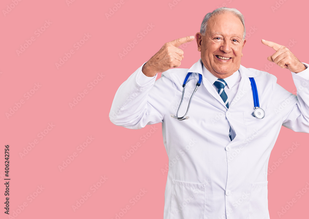 Senior handsome grey-haired man wearing doctor coat and stethoscope smiling pointing to head with both hands finger, great idea or thought, good memory Senior handsome grey-haired man wearing doctor coat and stethoscope smiling pointing to head with both hands finger, great idea or thought, good memory