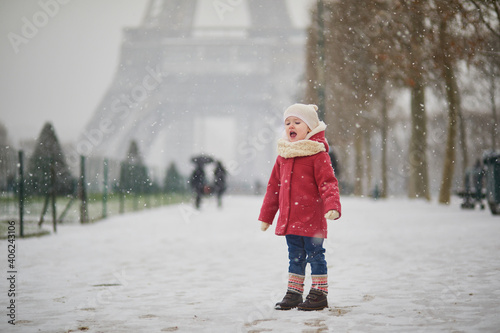 Photography Adorable toddler girl near the Eiffel tower on a day with heavy snowfall in Pari