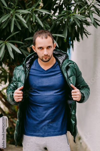 man wearing blue t-shirt mockup and jacket outdoors. Male in blank blue t-shirt v collar, front view outdoors. Design men t shirt template and mock-up for print 