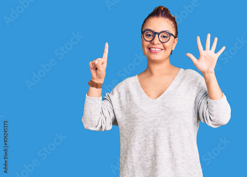 Young latin woman wearing casual clothes showing and pointing up with fingers number six while smiling confident and happy.