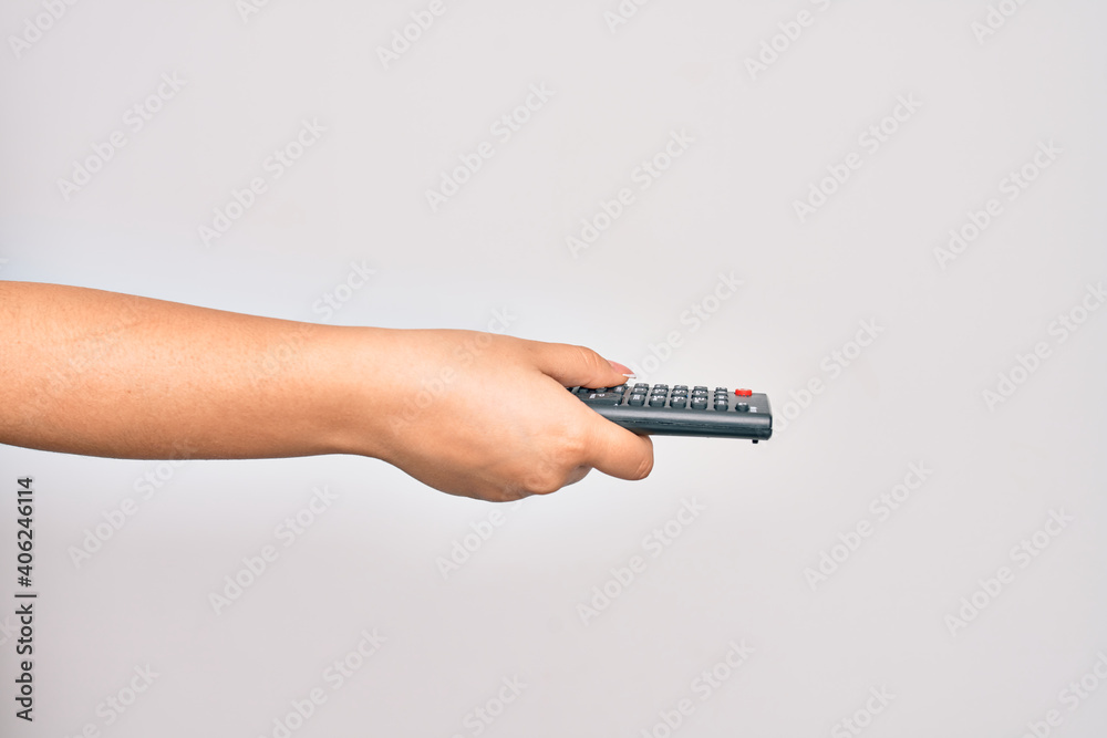Hand of caucasian young woman changing television channel holding tv remote control over isolated white background Hand of caucasian young woman changing television channel holding tv remote control over isolated white background