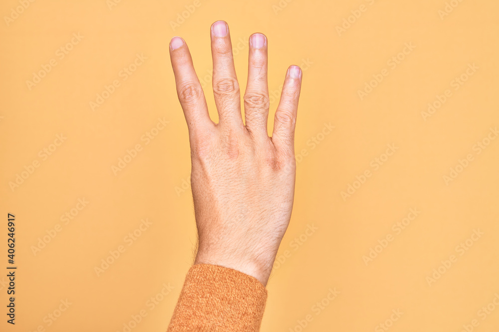 Hand of caucasian young man showing fingers over isolated yellow background counting number 4 showing four fingers Hand of caucasian young man showing fingers over isolated yellow background counting number 4 showing four fingers