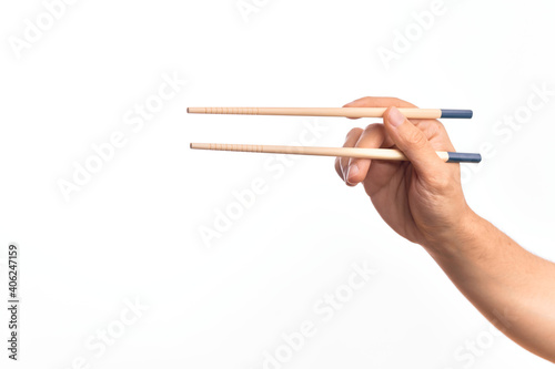 Hand of caucasian young man holding chopsticks over isolated white background