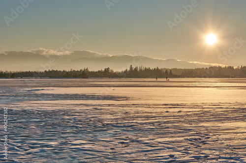 Sunset above a frozen mountain lake in the German alps. Sunset sky above the frozen Kirchsee lake in Bavaria  Germany.