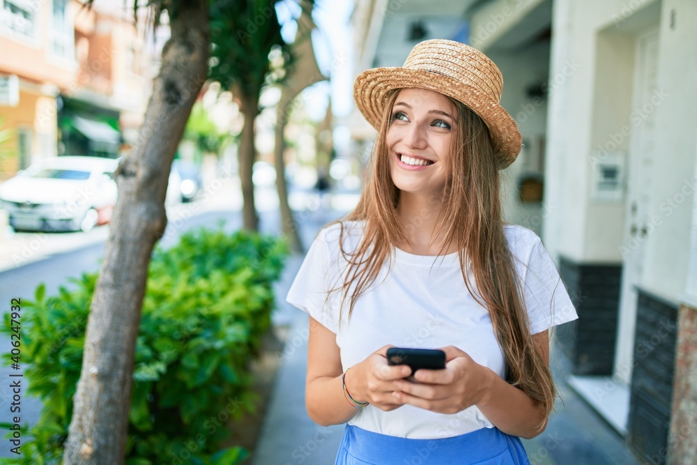 Fototapeta premium Young blonde woman on vacation smiling happy using smartphone at street of city