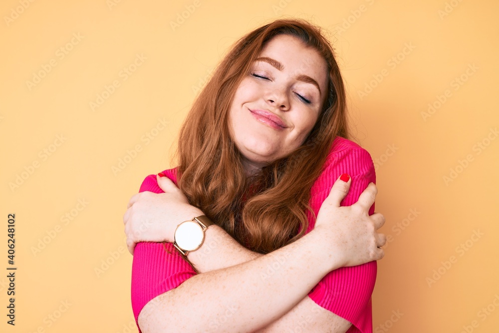 Young redhead woman wearing casual clothes hugging oneself happy and positive, smiling confident. self love and self care Young redhead woman wearing casual clothes hugging oneself happy and positive, smiling confident. self love and self care