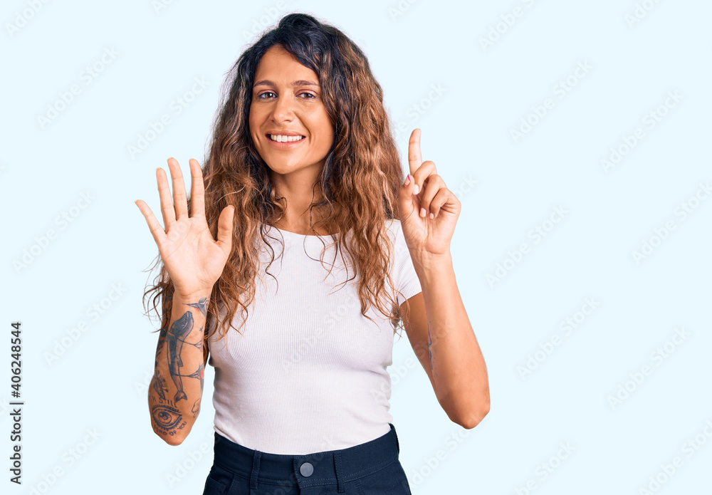 Young hispanic woman with tattoo wearing casual white tshirt showing and pointing up with fingers number six while smiling confident and happy. Young hispanic woman with tattoo wearing casual white tshirt showing and pointing up with fingers number six while smiling confident and happy.