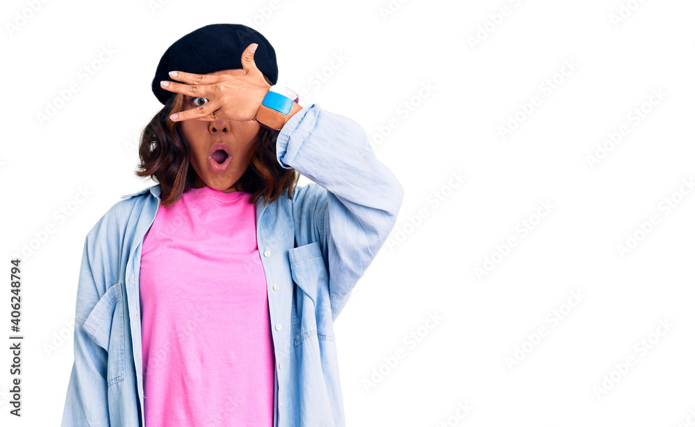 Young beautiful mixed race woman wearing french look with beret peeking in shock covering face and eyes with hand, looking through fingers with embarrassed expression. Young beautiful mixed race woman wearing french look with beret peeking in shock covering face and eyes with hand, looking through fingers with embarrassed expression.
