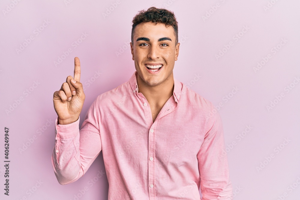 Hispanic young man pointing up with fingers smiling and laughing hard out loud because funny crazy joke.