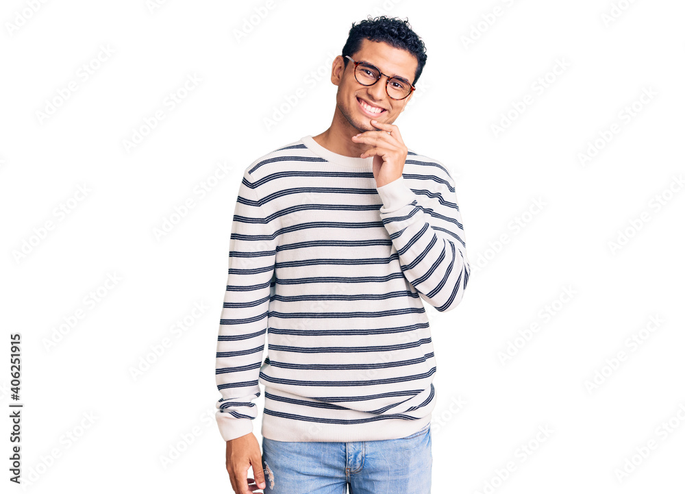 Hispanic handsome young man wearing casual clothes and glasses looking confident at the camera with smile with crossed arms and hand raised on chin. thinking positive. Hispanic handsome young man wearing casual clothes and glasses looking confident at the camera with smile with crossed arms and hand raised on chin. thinking positive.