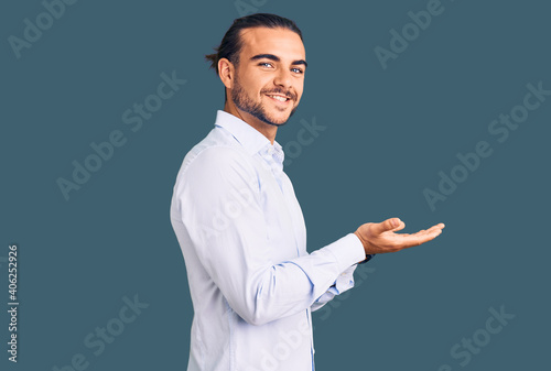 Young handsome man wearing business clothes pointing aside with hands open palms showing copy space, presenting advertisement smiling excited happy