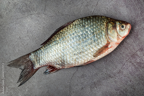 Carp fish not cleaned of scales on a gray mottled background