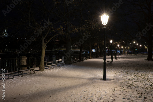 .light from street lights and a walkway sunken with snow in the center of Prague in the park at night